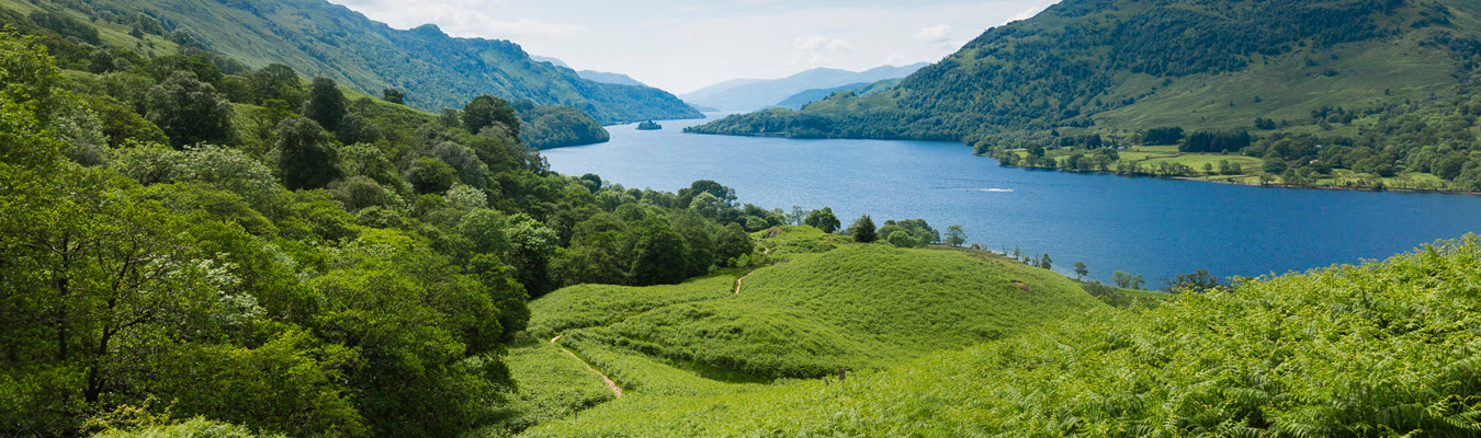 Peaceful green hills are surrounding a body of calm blue waters. 