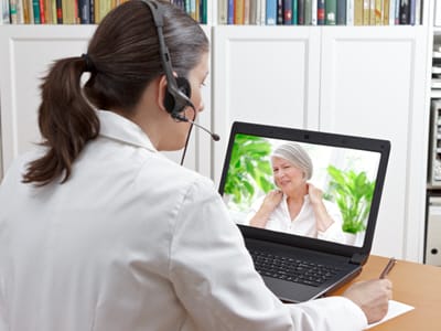 A psychologist talks with a patient on a laptop through Zoom.